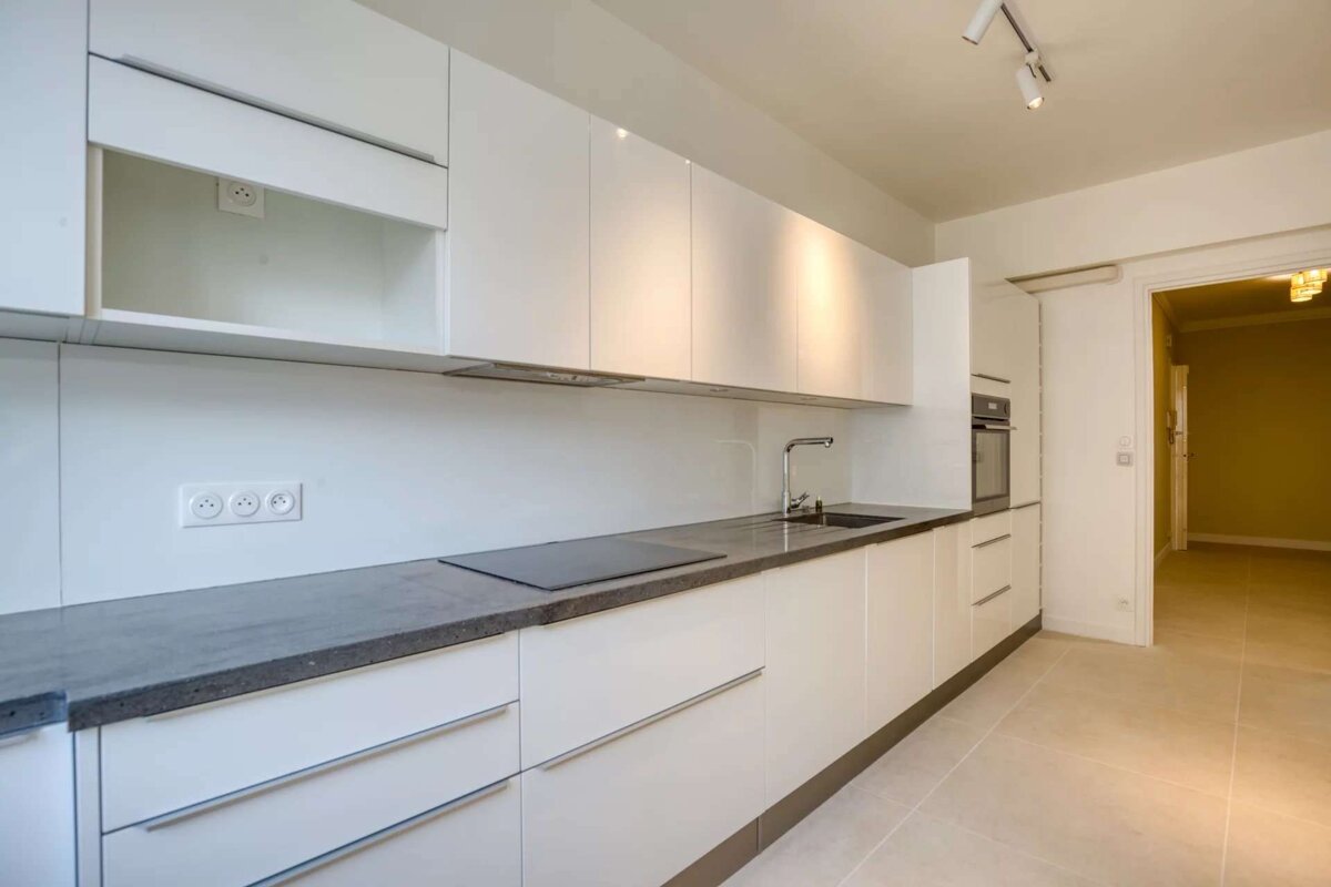 A kitchen with white cabinets and black counter tops