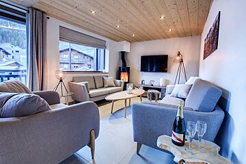 A bottle of champagne sits on a wooden table in a living room