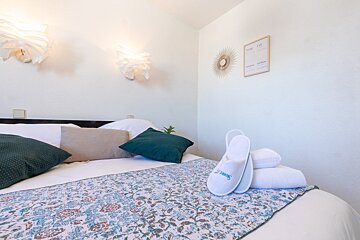 A pair of slippers on a bed with a floral blanket