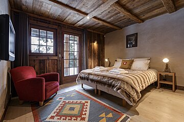 A bedroom with a bed a chair and a rug