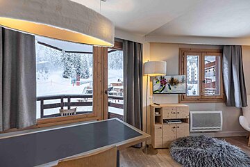 A room with a table and a television with a picture of skiers on it