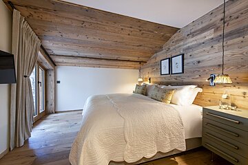 A bedroom with wooden walls and a large bed