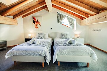 A bedroom with two beds and a painting on the wall