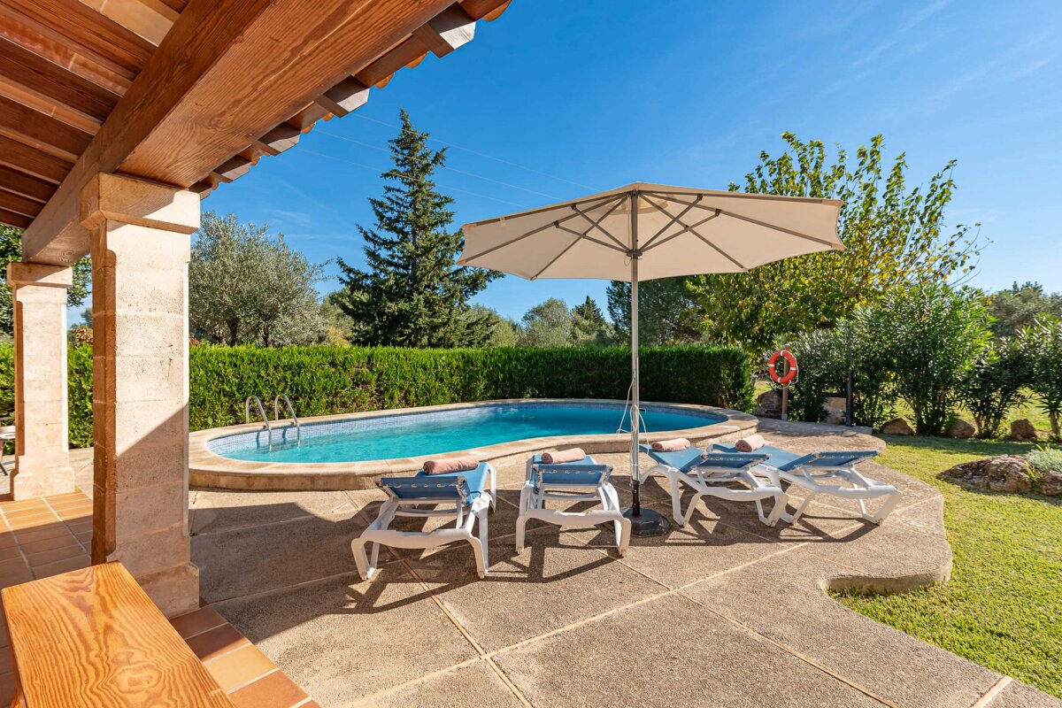 A swimming pool with chairs and an umbrella in front of it