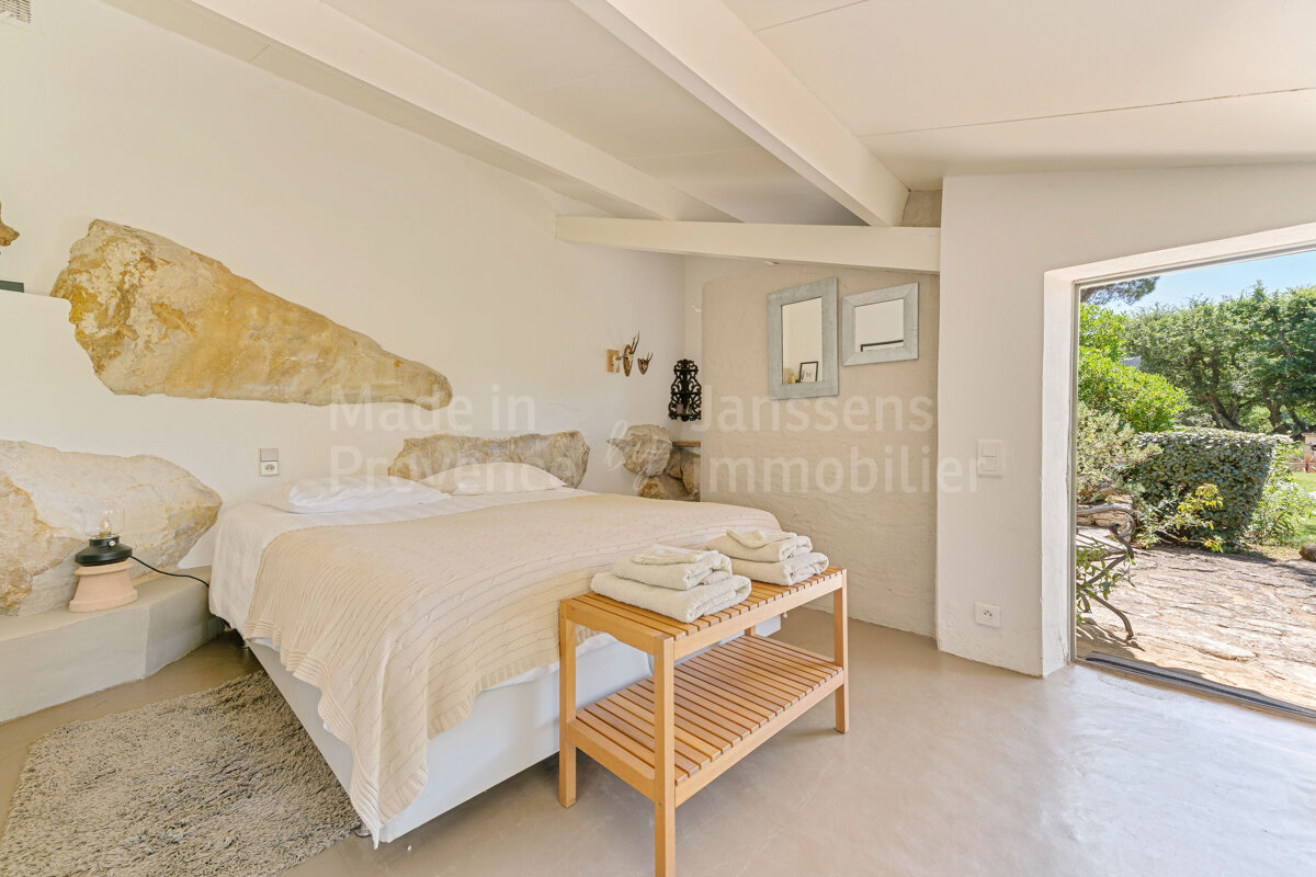 A bedroom with a large bed and a shelf with towels on it and the words made in provence on the wall
