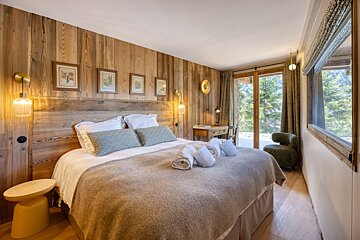 A bedroom with wood paneling and a large bed