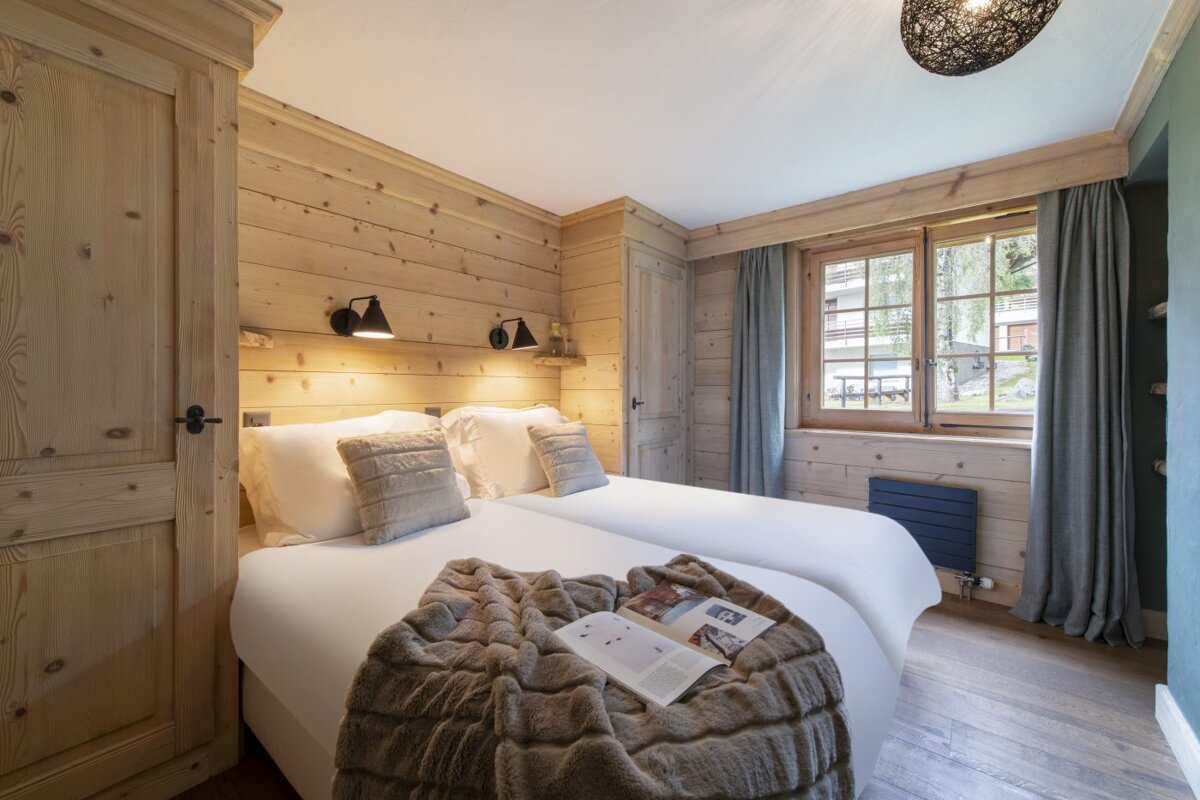 A bedroom with two beds and a book on the ottoman
