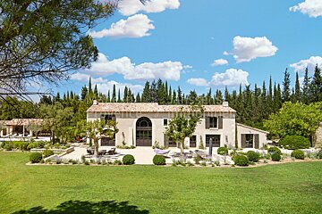A large house sits in the middle of a lush green field