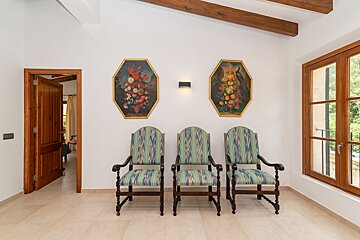 A room with three chairs and two paintings on the wall