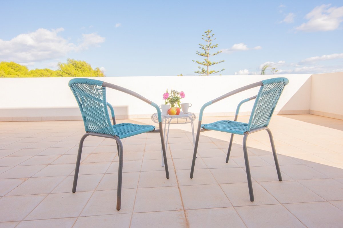 Two chairs and a table with a vase of flowers on it