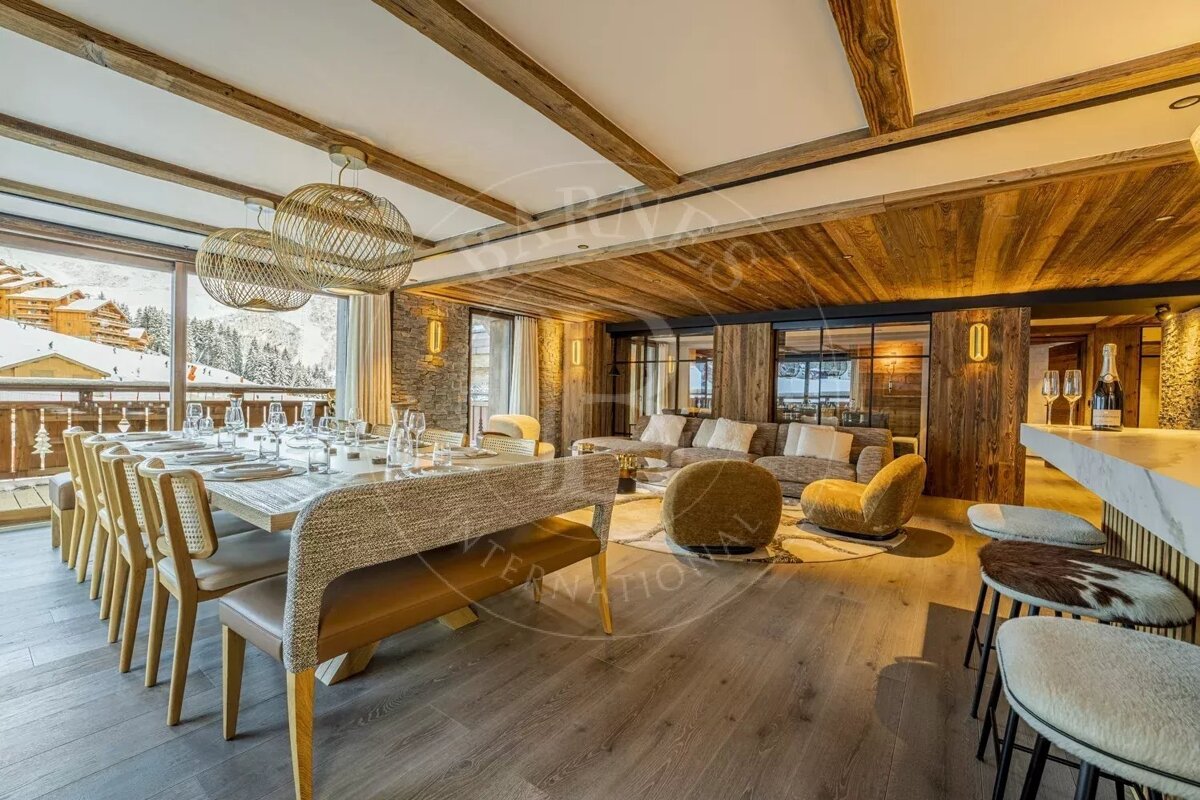 Luxurious alpine chalet with warm wood accents, a large dining table, a cozy living area, and snowy mountain views.