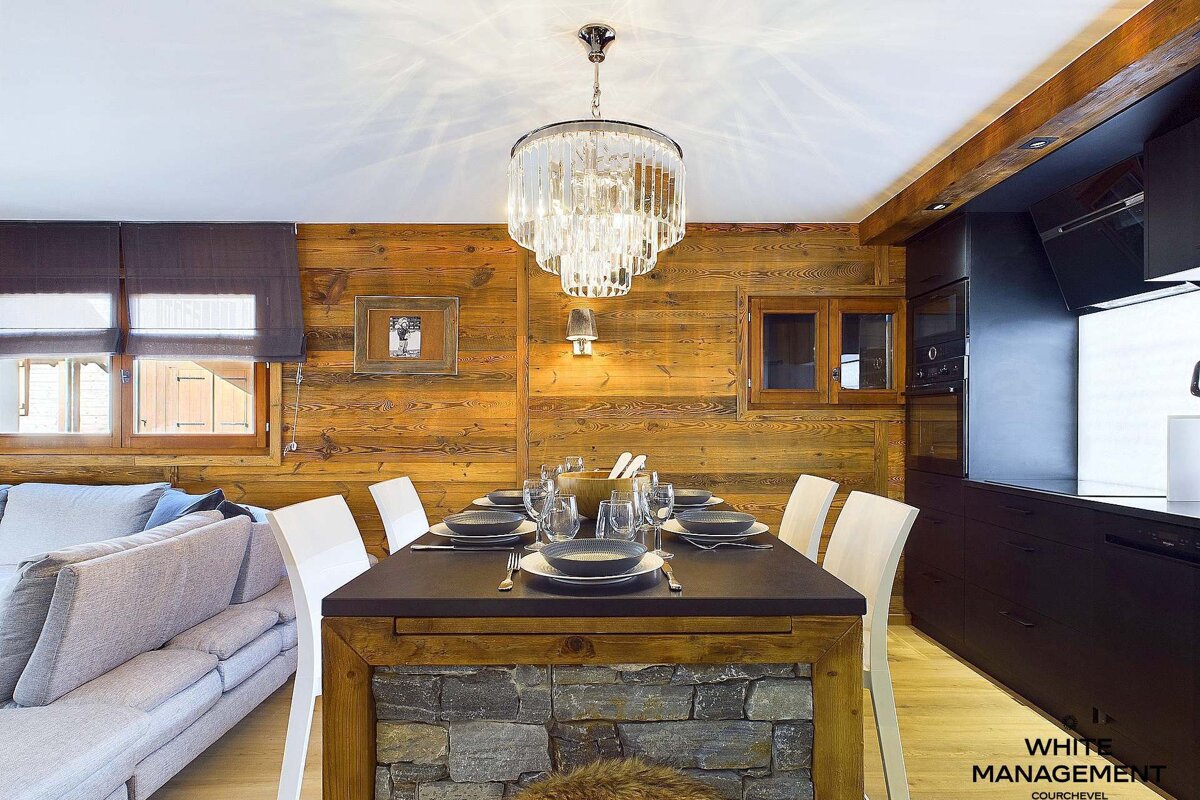 A dining room with a chandelier and a white management logo