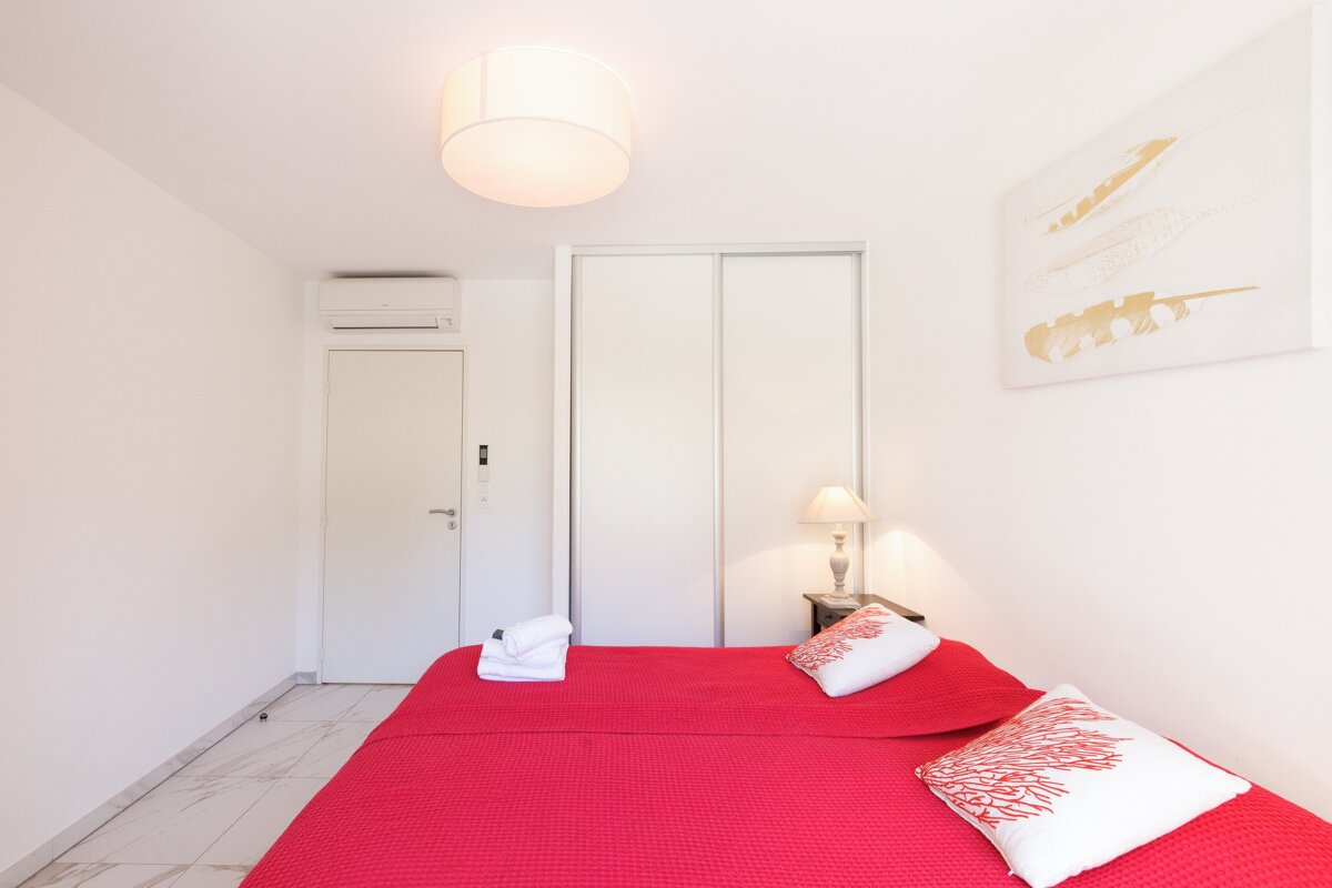 A bedroom with a red bed and white pillows