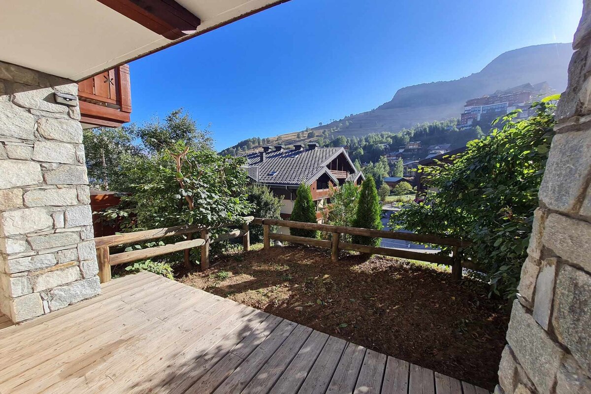 A wooden deck with a fence surrounding it and a mountain in the background