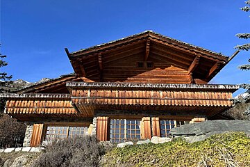 A large wooden house with a blue sky in the background