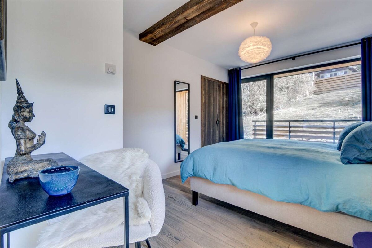 A bedroom with a bed and a table with a blue bowl on it
