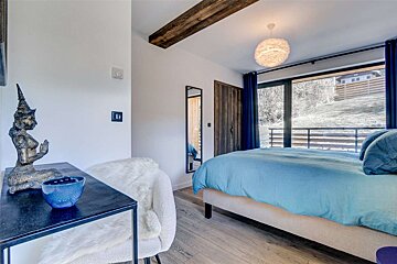 A bedroom with a bed and a table with a blue bowl on it