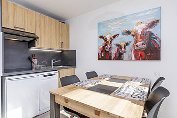 A painting of three cows hangs above a dining table