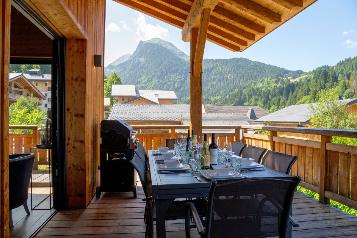 A table and chairs on a balcony with a mountain in the background