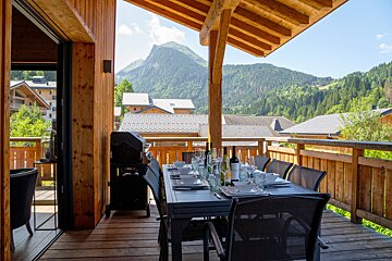 A table and chairs on a balcony with a mountain in the background