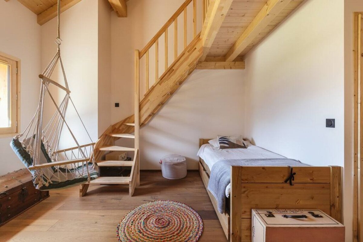 A bedroom with a wooden staircase and a hammock