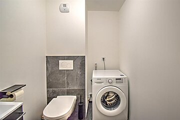 A samsung washing machine sits next to a toilet in a bathroom