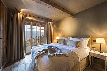 A bedroom with a large bed and two lamps