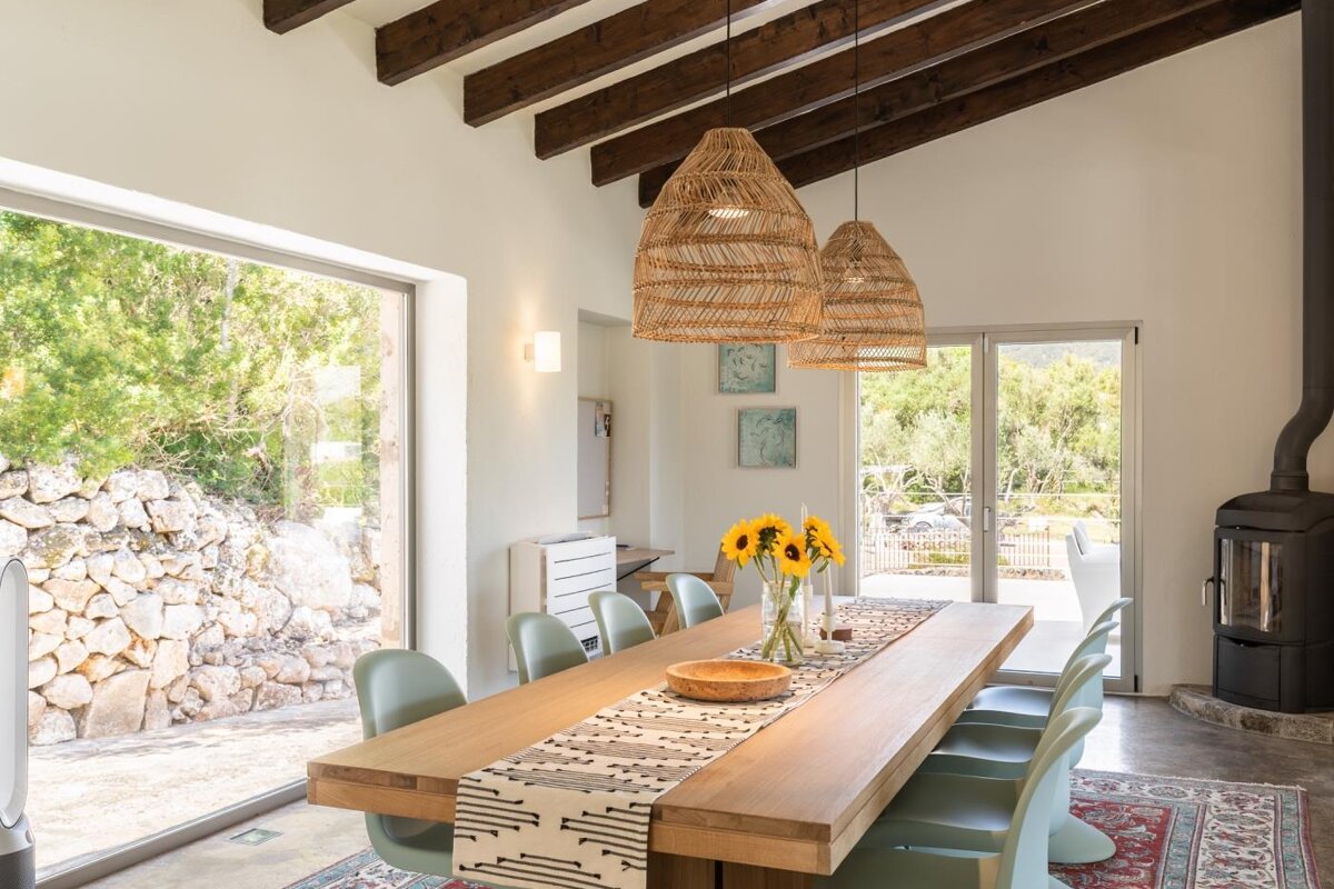 A dining room table with a vase of sunflowers on it