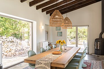 A dining room table with a vase of sunflowers on it
