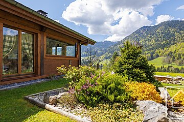 A house in the mountains with a garden in front of it