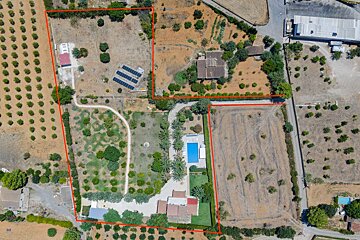 Aerial view of multiple properties outlined in red, featuring houses, a swimming pool, solar panels, agricultural fields, and natural vegetation.