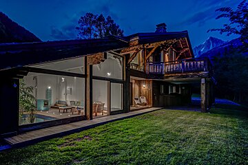 A house with a lot of windows is lit up at night