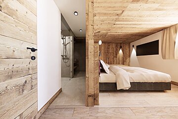 A rustic modern bedroom featuring light wood paneling, a cozy bed, and an open entryway leading into a bathroom.