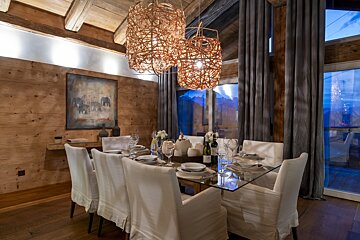 A dining room with a glass table and white chairs