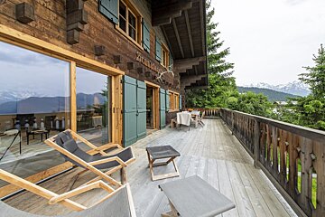 A wooden house with a balcony and chairs and a sign that says zimmermann