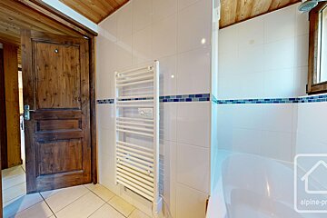 A bathroom with a towel rack and a bathtub with alpine-pro written on the wall