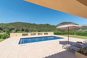 A large swimming pool is surrounded by chairs and umbrellas