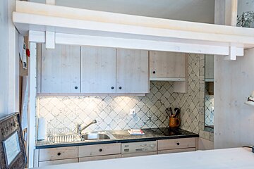 A small kitchen with white cabinets and a sink
