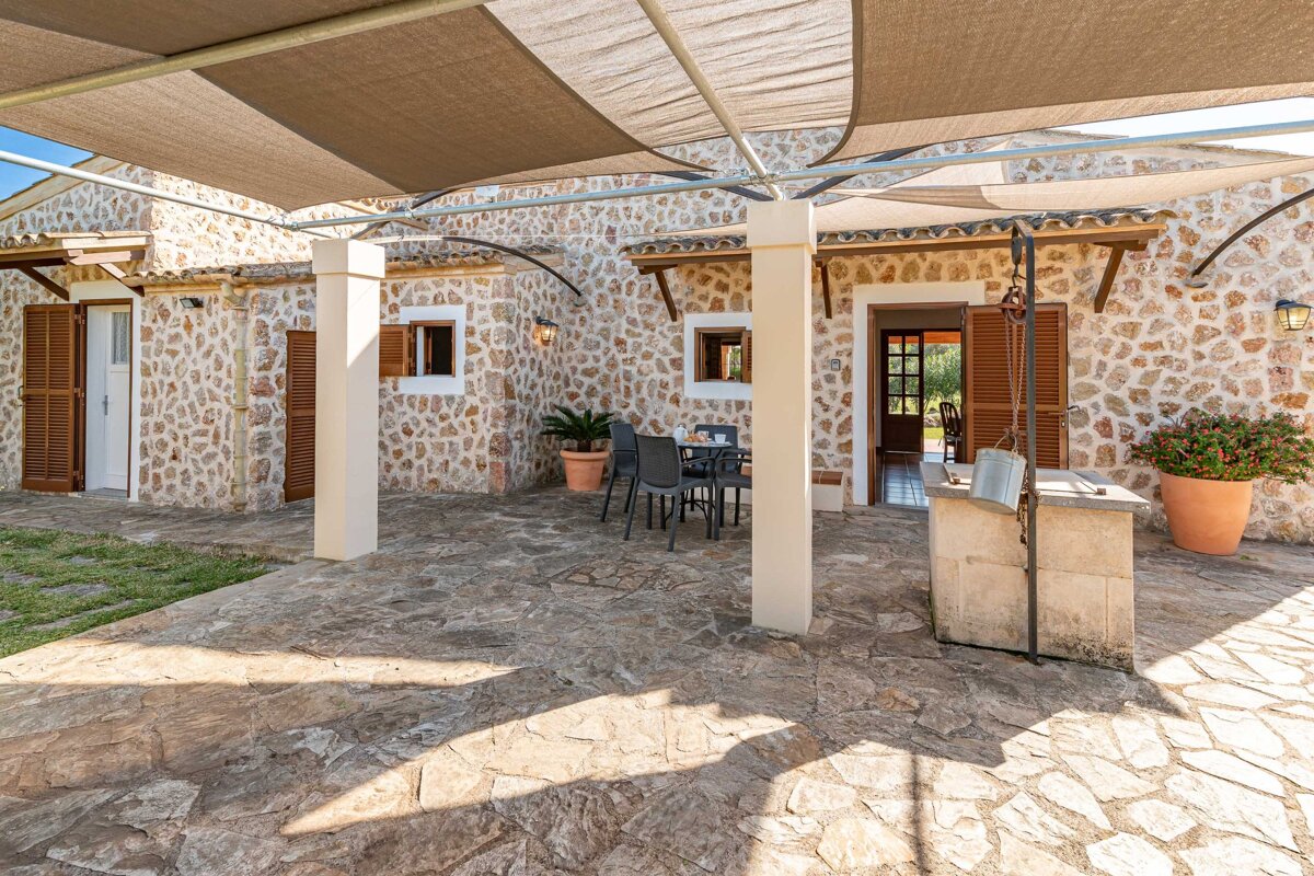 A stone house has a patio with a table and chairs under an awning