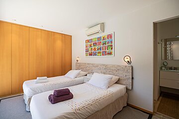 A bedroom with two beds and a painting on the wall