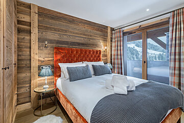 A bedroom with a large bed and a sliding glass door