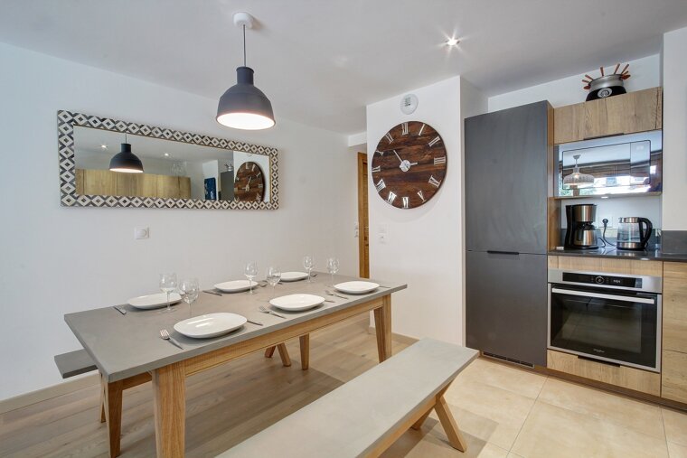 A kitchen with a table and a clock on the wall
