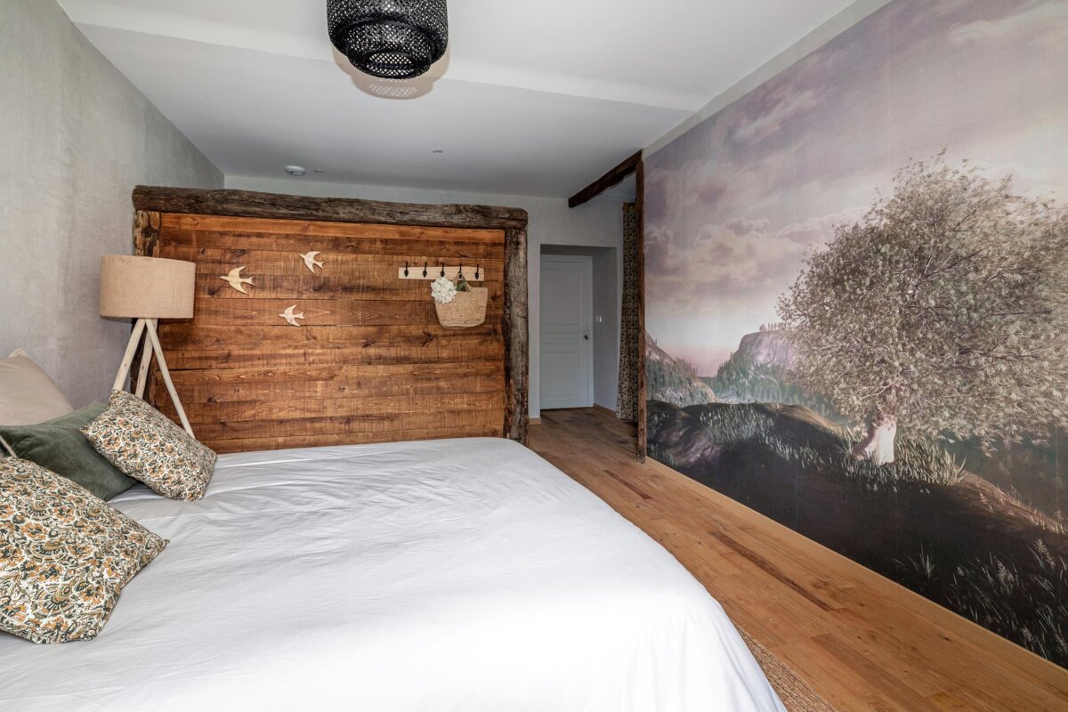 A bedroom with a wooden headboard and a painting on the wall