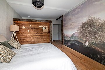 A bedroom with a wooden headboard and a painting on the wall
