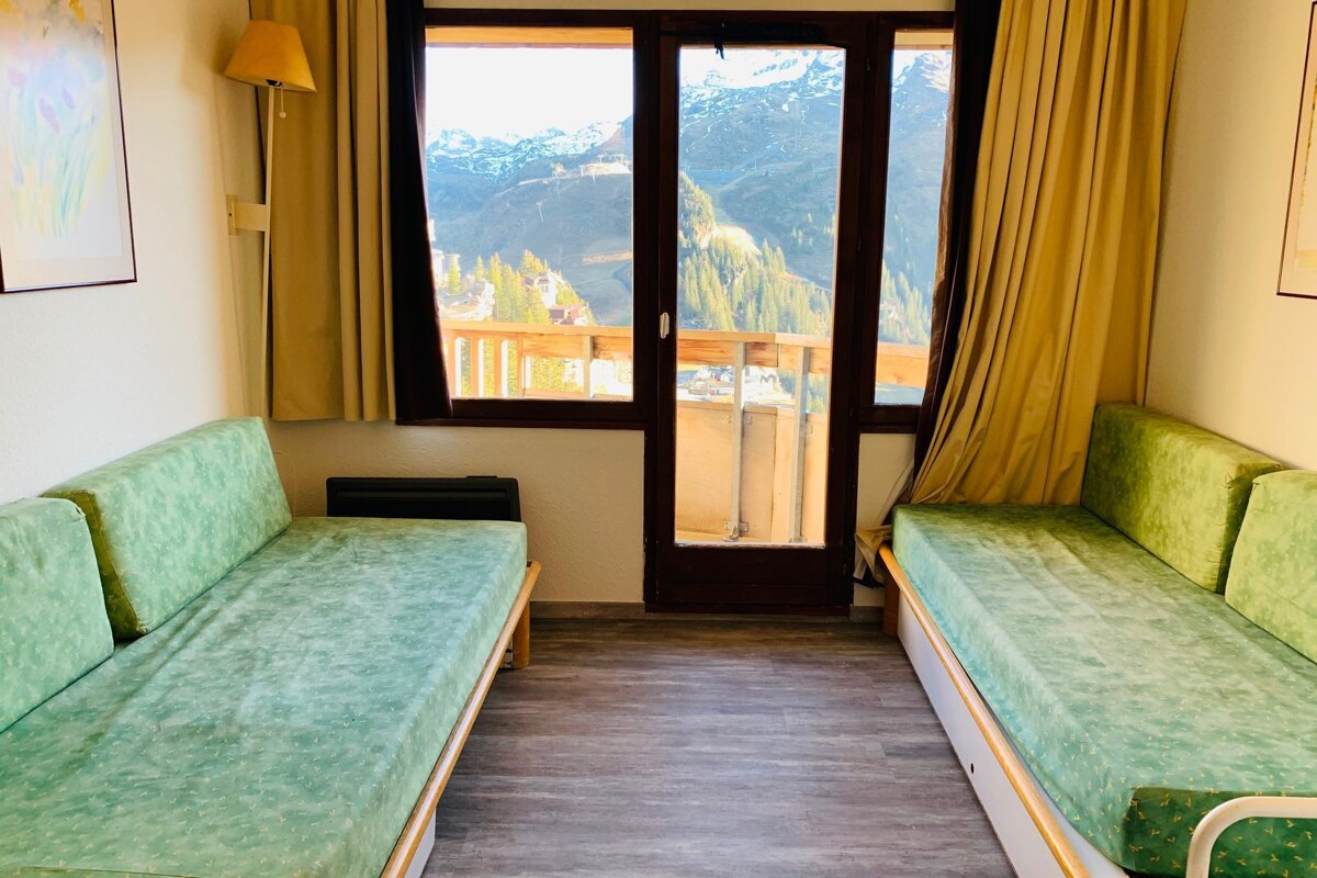 A living room with two green couches and a balcony