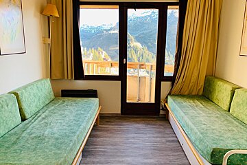 A living room with two green couches and a balcony