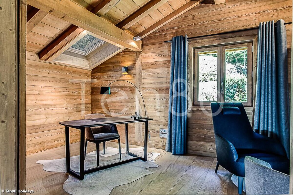 A wooden room with a desk and chair and the word holidays on the wall