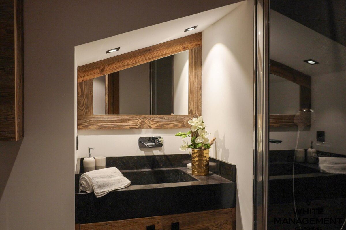 A bathroom with a sink and a mirror with a wooden frame