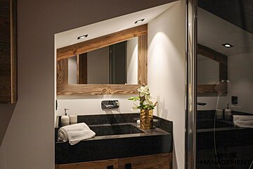 A bathroom with a sink and a mirror with a wooden frame