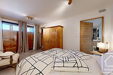 A bedroom with a large bed and a wooden wardrobe